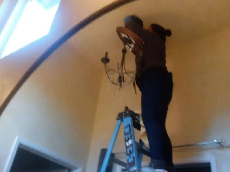 Electrician installing a chandelier in a Middleton residence